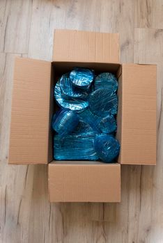 Glassware wrapped with blue wrapping nylon at the bottom of a cardboard box. Glassware wrapped in a box. Top view. Flat lay. Copy space. High quality photo