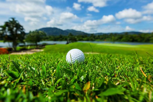 Golf ball on course, morning landscape of field and mountains