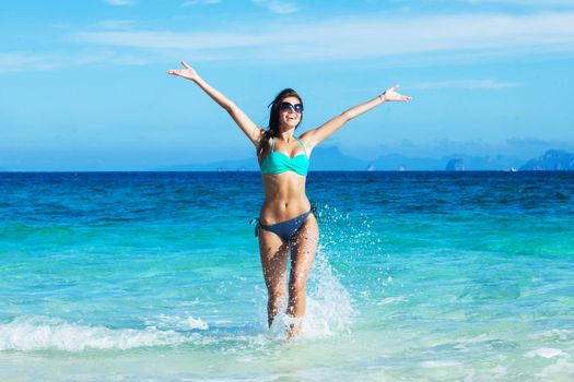 Beautiful happy woman in splashing in the sea with raised arms