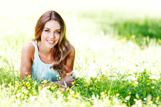 Beautiful healthy Young Woman relaxing on the green grass and smiling