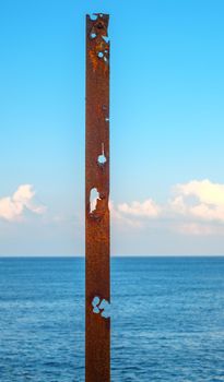 a rusty pipe with the sea behind it