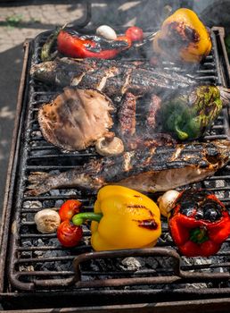 Barbecuing an assortment of red, yellow and green capsicum,  mushrooms, and trout fish