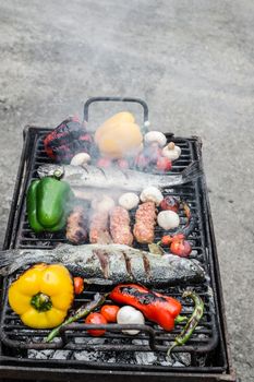 Barbecuing an assortment of red, yellow and green capsicum,  mushrooms, and trout fish