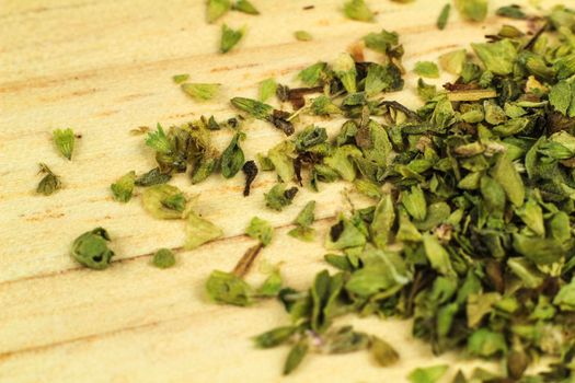 Crushed dried oregano to spice up dishes on brown wooden board