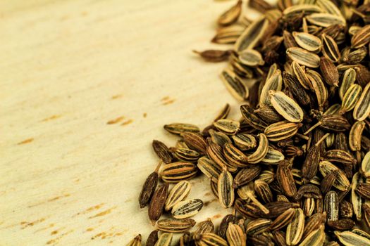 Organic dried fennel seeds on brown wooden board