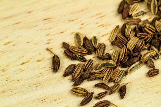 Organic dried fennel seeds on brown wooden board