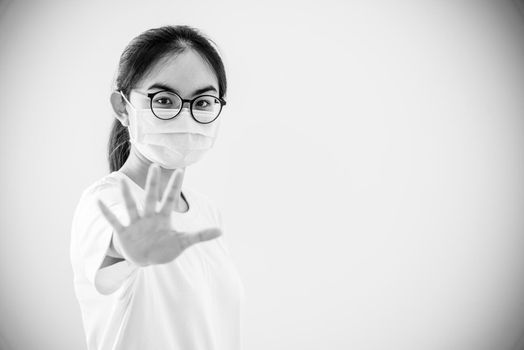 Black and white color portrait Asian young woman wears glasses and mask to protect against Coronavirus, girl show hand stop coronavirus outbreak, copy space for stop virus Covid 19 concept background