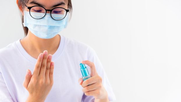 Asian young woman wears mask protect wash hand cleaning with alcohol spray stop coronavirus outbreak or prevent the spread of the Covid 19 virus isolated on white background, Good hygiene concept 16:9