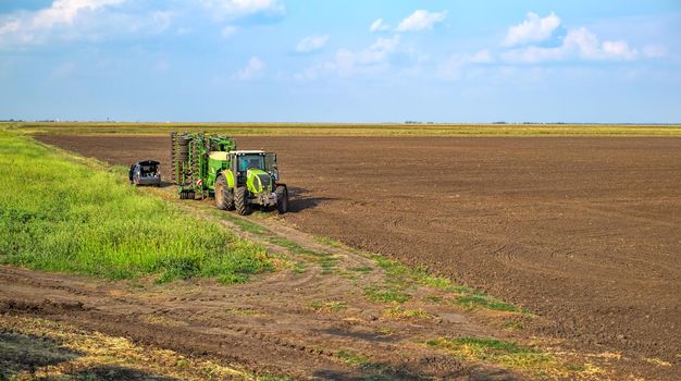 Giurgiu, Romania - August 29, 2018. Agriculture green tractor sowing seeds and cultivating field in late afternoon