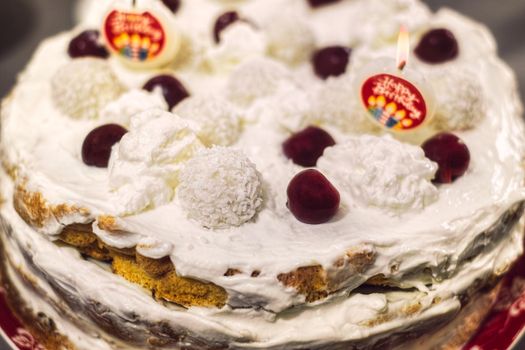 biscuit cake with whipped cream candles and cherries