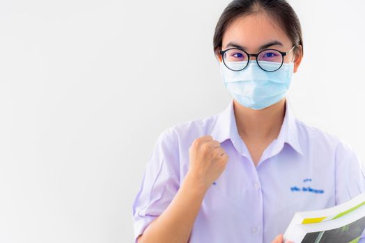 Student Asian young woman wears a mask to protect Coronavirus spread, Thai girl to encourage show fist symbol to fight and strong on white background healthy care from Covid 19 virus outbreak concept