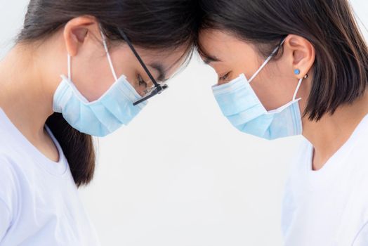 Two woman mother and daughter wear a mask to prevent the coronavirus outbreak with a sad feeling, Head against each other to comfort encourage to fight health problems and illness on white background