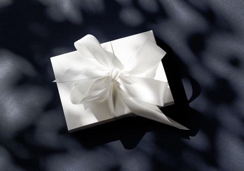 Anniversary celebration, shop sale promotion and luxe surprise concept - Luxury holiday white gift box with silk ribbon and bow on black background, luxe wedding or birthday present