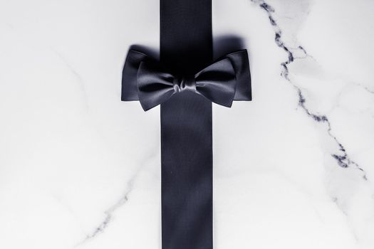 Holiday gift, decoration and sale promotion concept - Black silk ribbon and bow on marble background, flatlay