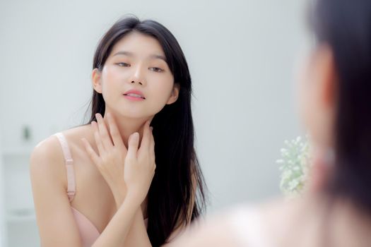 Beautiful sexy young asian woman looking mirror applying cream on neck and message, beauty girl applying body lotion skin care for health and soft hydration, treatment and cosmetic with moisturizer.