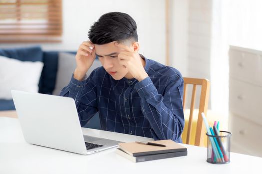 Young asian business man headache during working on laptop computer with deadline on desk at home, businessman with failure exhausted and tired, stress and worried, frustrated and unsuccessful.