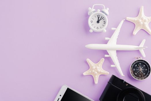 World Tourism Day, Top view of minimal model plane, airplane, starfish, alarm clock, compass and smartphone blank screen, studio shot isolated on purple background, accessory flight holiday concept