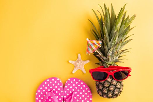 Celebrate Summer Pineapple Day Concept, Top view flat lay of funny fresh pineapple in sunglasses with starfish and slipper, in studio isolated on yellow background, Holiday summertime in tropical