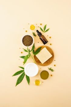 Alternative medicine, natural cosmetics. cbd oil and cannabis leaves cosmetics top view on orange background, flat lay