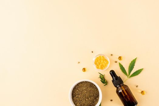 Alternative medicine, natural cosmetics. cbd oil and cannabis leaves cosmetics top view on orange background, flat lay