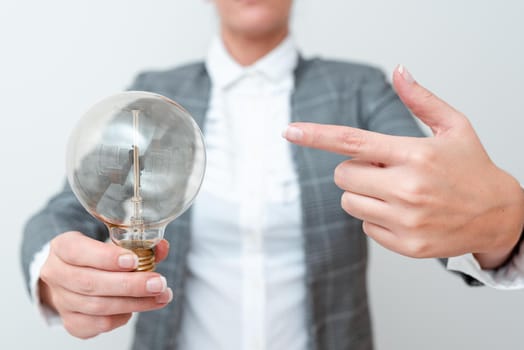 Lady Pointing To Lamp Held In Hand In Formal Outfit Presenting New Ideas For Project, Business Woman Carying Bulb Exhibiting Lately Released Technologies, Lightbulb Veiwing Fresh Idea.