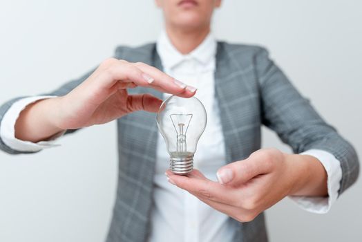 Lady Carrying Lightbulb With Two Hands In Formal Outfit Presenting New Ideas For Project, Business Woman Holding Bulbs In Hands Showing Late Technologies, Lamp Exhibiting Fresh Opinion.