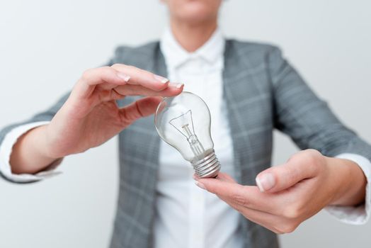 Lady Carrying Lightbulb With Two Hands In Formal Outfit Presenting New Ideas For Project, Business Woman Holding Bulbs In Hands Showing Late Technologies, Lamp Exhibiting Fresh Opinion.