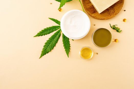 Alternative medicine, natural cosmetics. cbd oil and cannabis leaves cosmetics top view on orange background, flat lay