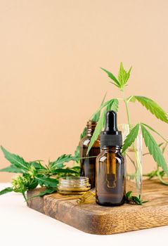 Alternative medicine, natural cosmetics. cbd oil and cannabis leaves cosmetics front view on orange background, copy space