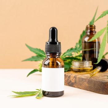 Alternative medicine, natural cosmetics. cbd oil and cannabis leaves cosmetics front view on orange background, copy space
