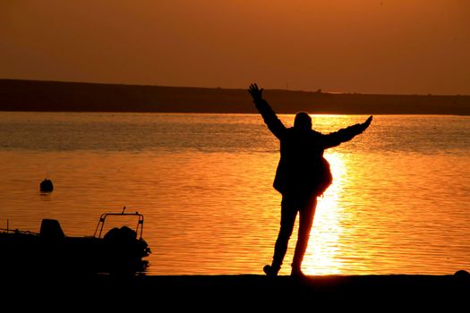 Young woman silhouette having fun at sunset on the banks of the Douro River in Oporto, Portugal.