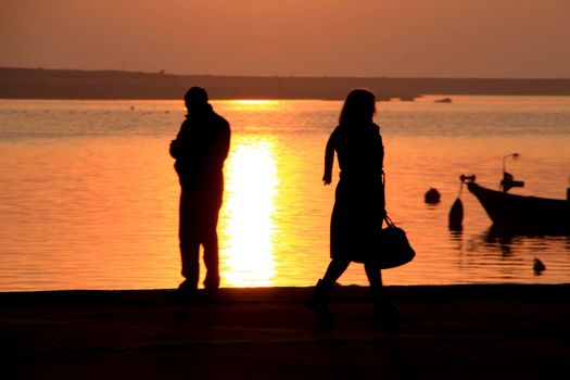 People relaxing and walking at sunset along the banks of the Douro River in Oporto, Portugal.