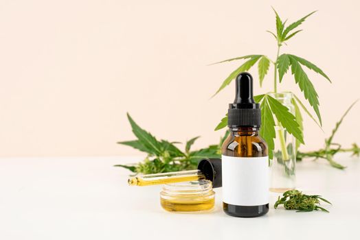 Alternative medicine, natural cosmetics. cbd oil and cannabis leaves cosmetics front view on orange background, copy space