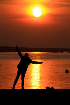 Young woman silhouette having fun at sunset on the banks of the Douro River in Oporto, Portugal.