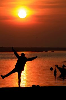 Young woman silhouette having fun at sunset on the banks of the Douro River in Oporto, Portugal.