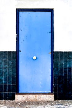 Blue door and white and blue tiled facade in Alicante, Spain.