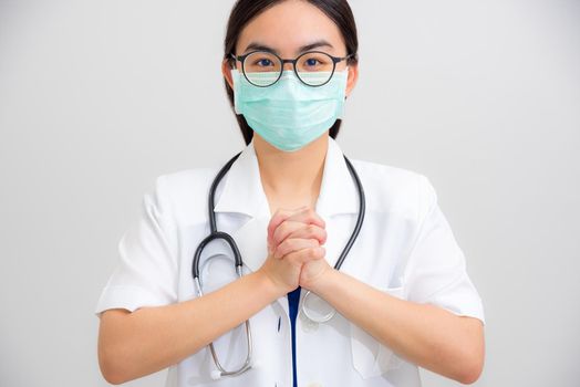 Portrait beautiful Asian woman doctor with stethoscope and mask to protect Corona Virus clasp hand gesture of beg for help cooperation, work together confederate to stop the epidemic COVID 19 concept