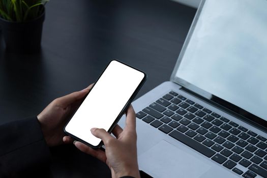 Woman using smartphone frameless mockup with blank screen in home office.