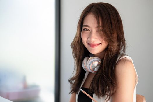 Portrait of young attractive asian woman looking at camera smiling with confident and positive lifestyle concept at office.