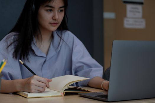 Close up hand of asian student taking note during online lesson with laptop, Study Education at home