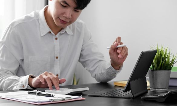 man accountant working with digital tablet computer and calculator for business and financial expense at home office.