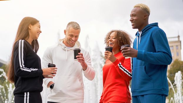 Multi-ethnic group teenage friends. African-american asian caucasian student spending time together Multiracial friendship Happy smiling People dressed colorful sportswear drink coffee outdoor