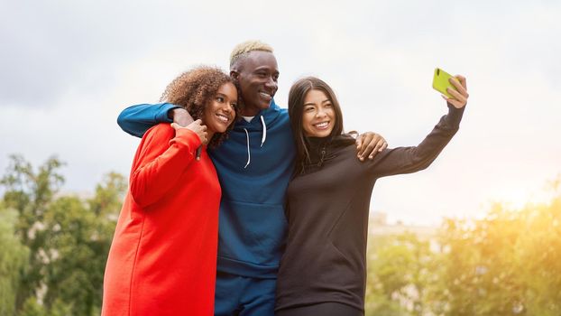 Multi ethnic friends outdoor taking a selfie on smartphone. Diverse group people Afro american asian spending time together Multiracial male female student meeting outdoors