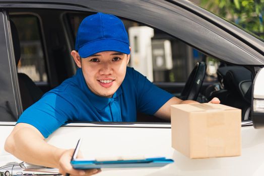 Asian young delivery man courier wear uniform in the car hold documents clipboard hand over to customer to signing signature for receipt of delivery package at door front house