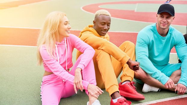 Multi-ethnic group teenage friends. African-american caucasian student spending time together Multiracial friendship Happy smiling People dressed colorful sportswear meeting outdoor sportground