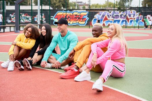 Multi-ethnic group teenage friends. African-american asian caucasian student spending time together Multiracial friendship Happy smiling People dressed colorful sportswear meeting outdoor sportground