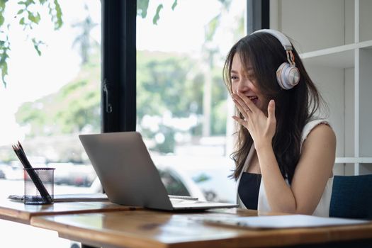 Joyful businesswoman sitting at desk looking at laptop screen talking with friend make video call