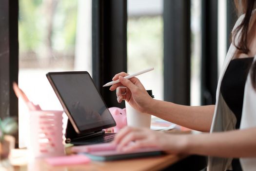 Close up hand of woman working with digital tablet with stylus pen and smart keyboard