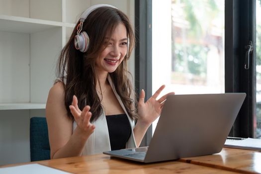 Side view shot smiling asian woman freelancer wearing headset, communicating with client via video computer call. Millennial pleasant professional female tutor giving online language class.