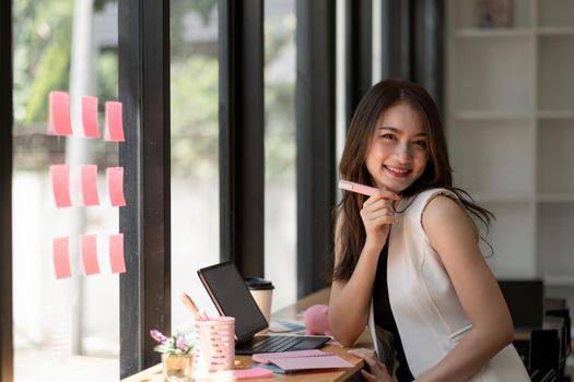 Portrait of attractive asian woman looking at camera smiling with confident working with smart tablet and positive lifestyle concept at cafe.
